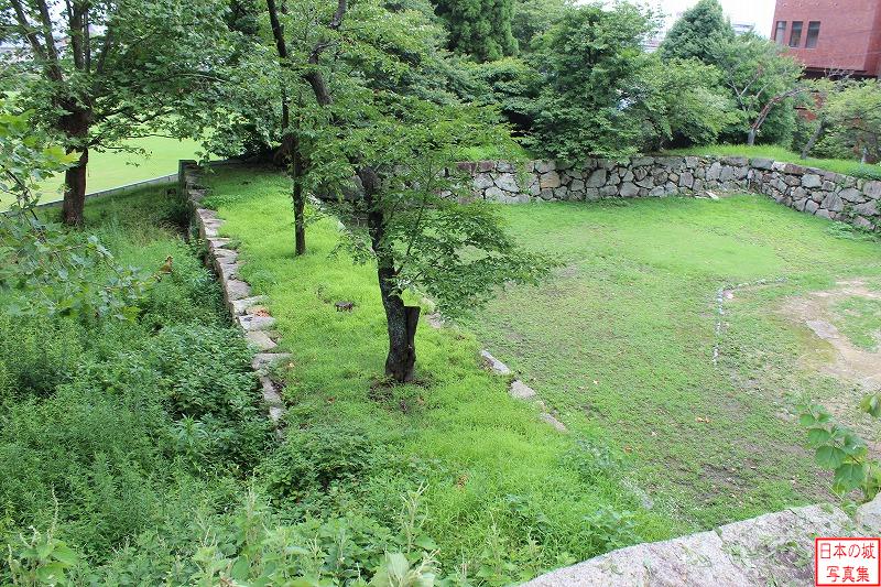 米子城 表中御門 表中御門跡を見下ろす。全体的に石垣が低く見えるが、約1.5メートル程地面に埋まっているので、往時は今よりも1.5メートル高い石垣であったとのこと。