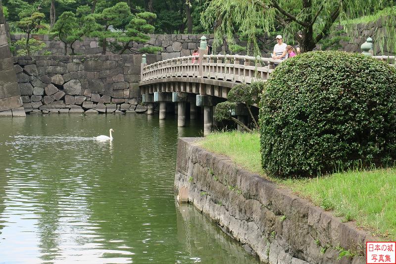 江戸城 和田倉橋 和田倉橋の下を潜り抜けようとする白鳥。白鳥の後ろには二筋の波が立ち、そのスピード感ある泳ぎが目に浮かぶ。橋の上にはその白鳥を暖かく見つめる一組の親子が。